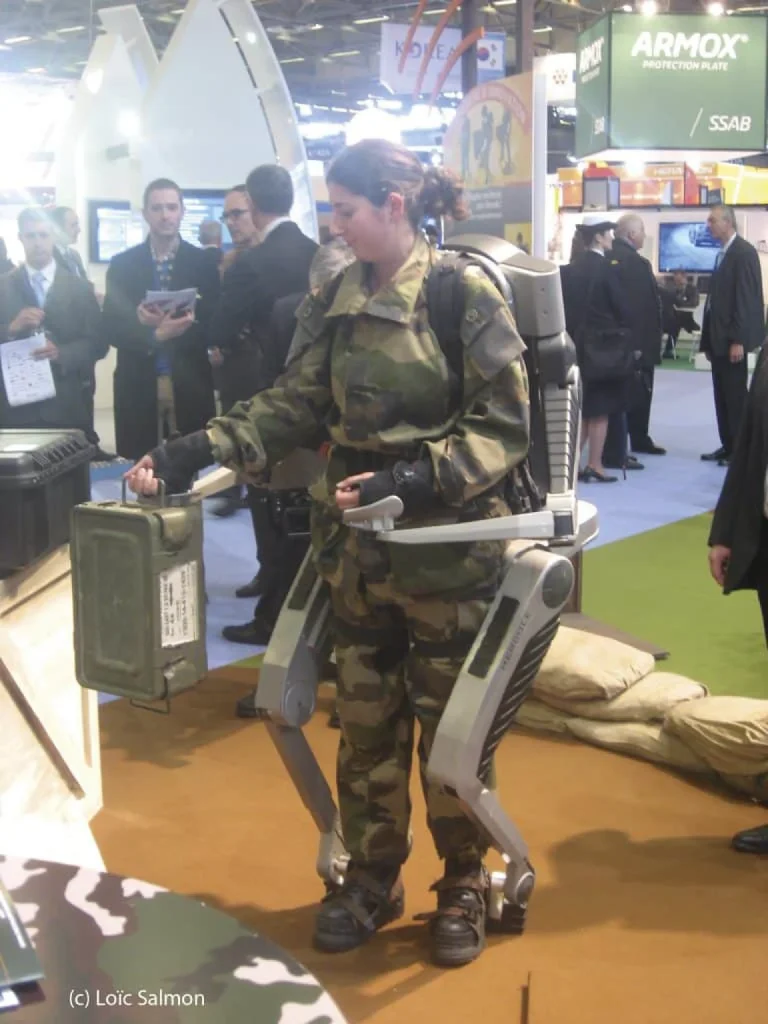 Une femme militaire avec un exosquelette qui "prend" tout son corps.