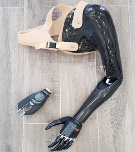 Photo d'une prothèse hybride. Elle s'accroche à l'épaule et il y a un bras hybride de couleur noire. 